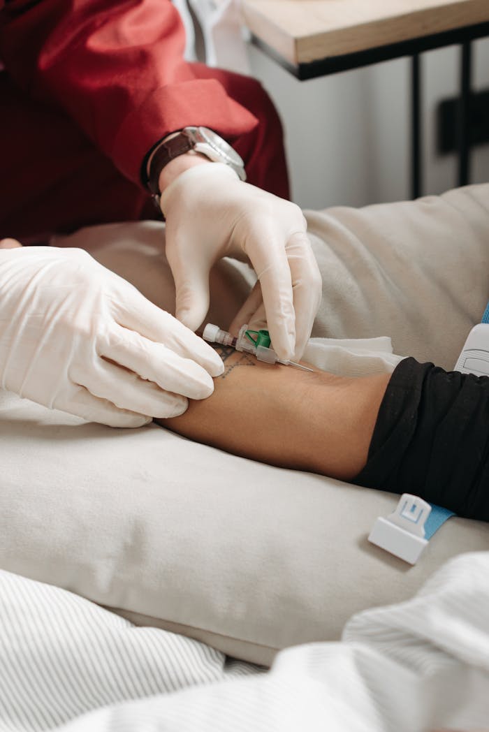 Doctor wearing gloves giving an injection to a patient's arm in a medical setting.