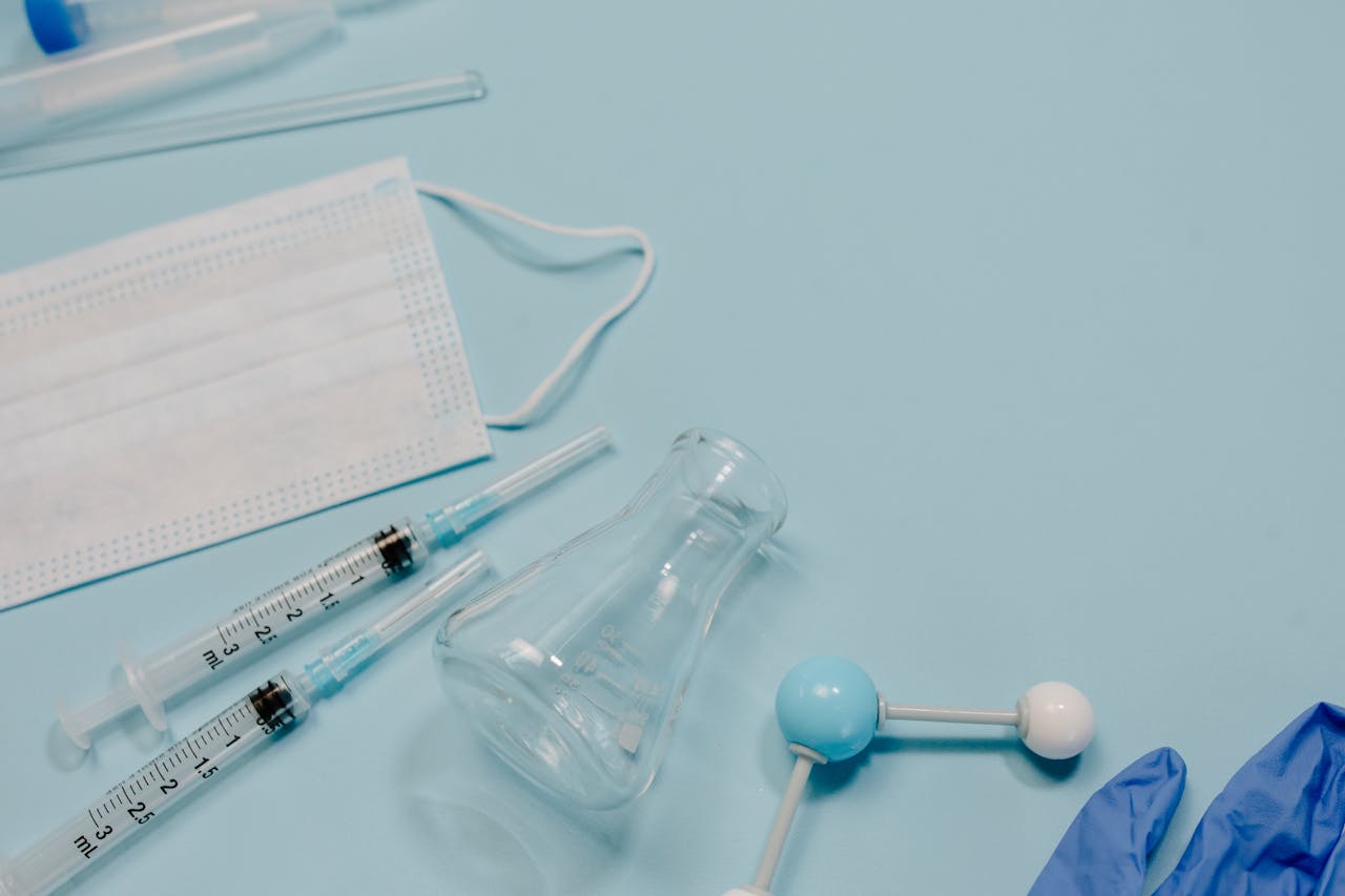 A collection of medical tools including syringes, face mask, and gloves on a blue background.